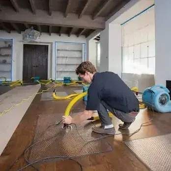 Technician laying floor drying mats on a wet hardwood floor